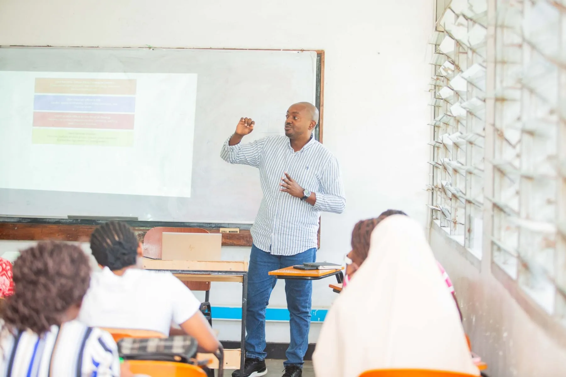 A trainer gesturing as he explains a slide to his class