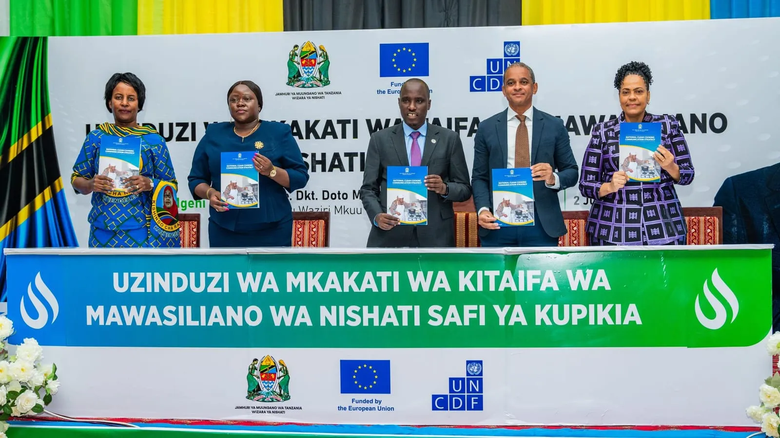 Officials on stage holding the National Clean Cooking Strategy document at its launch